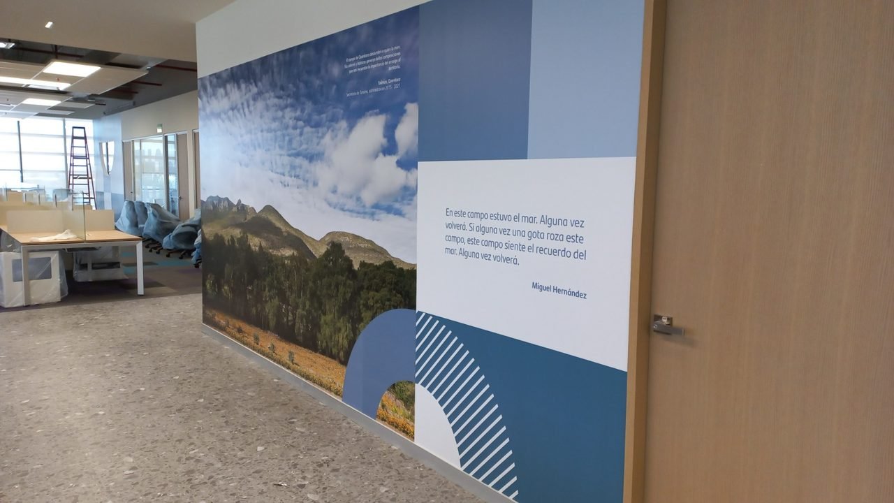 Mural fotográfico con cita en pasillo corporativo